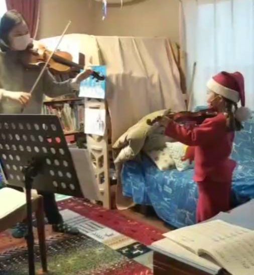 子供と一緒にバイオリンを弾いているバイオリン教師